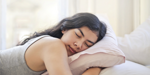 Female asleep hugging a pillow. Article: Bedtime audiobooks to release anxiety | Audible & Headspace